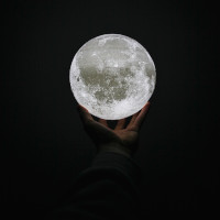 Immagine che mostra una piccola luna nella mano di un uomo.