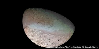 Tritone fotografato da Voyager 2. Visibile una calotta polare, uno strano terreno retato e delle macchie scure, forse geyser di azoto